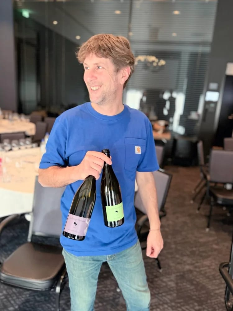Damien Delecheneau met twee La Grange Tiphaine-flessen op de hospitality-lounge