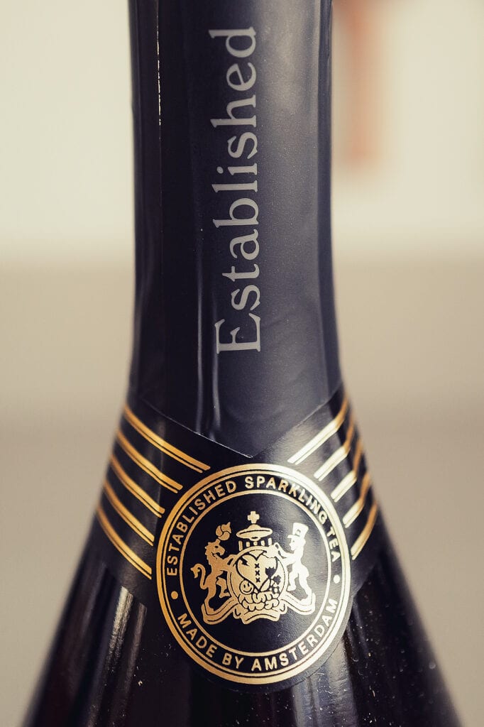 Close-up van de flessenhals van Est. Sparkling Tea met het woord Established en een gouden wapen-zegel