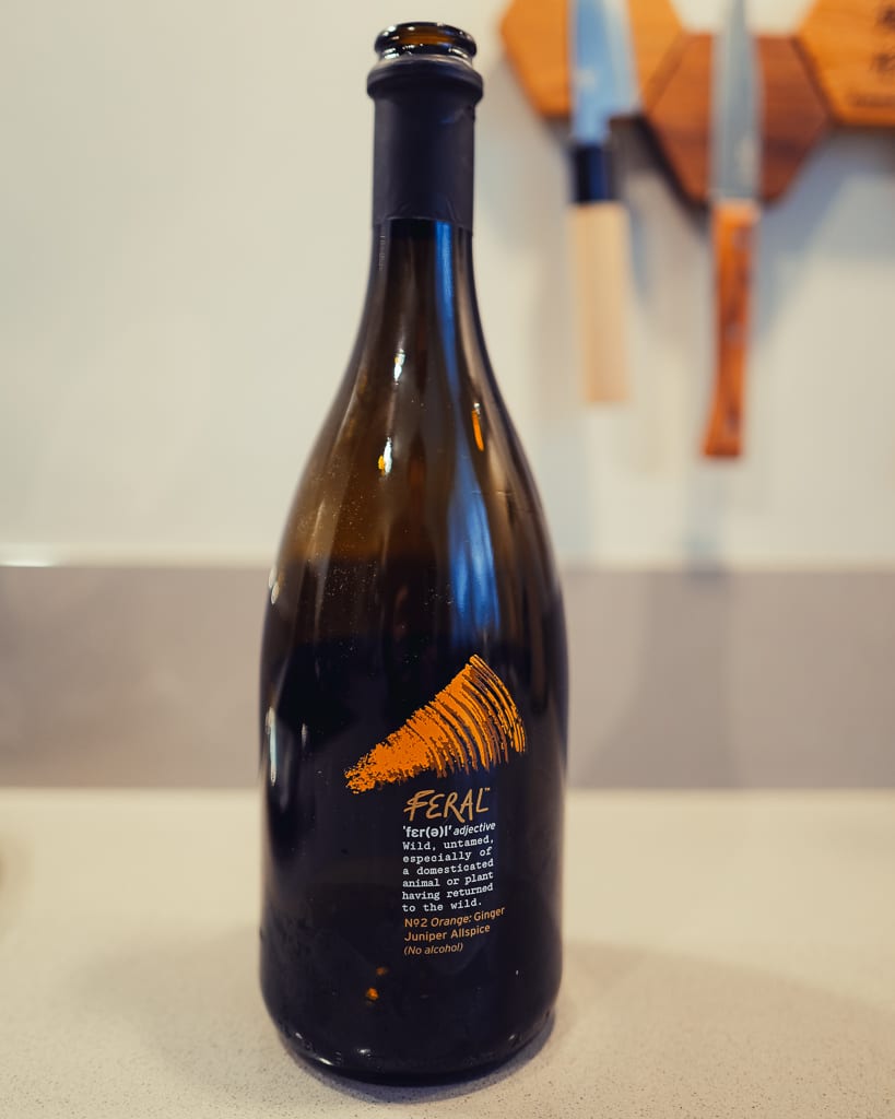 Donkere fles Feral No2 Orange met gember en jeneverbes, alcoholvrij, voor een keukenmuur met messen