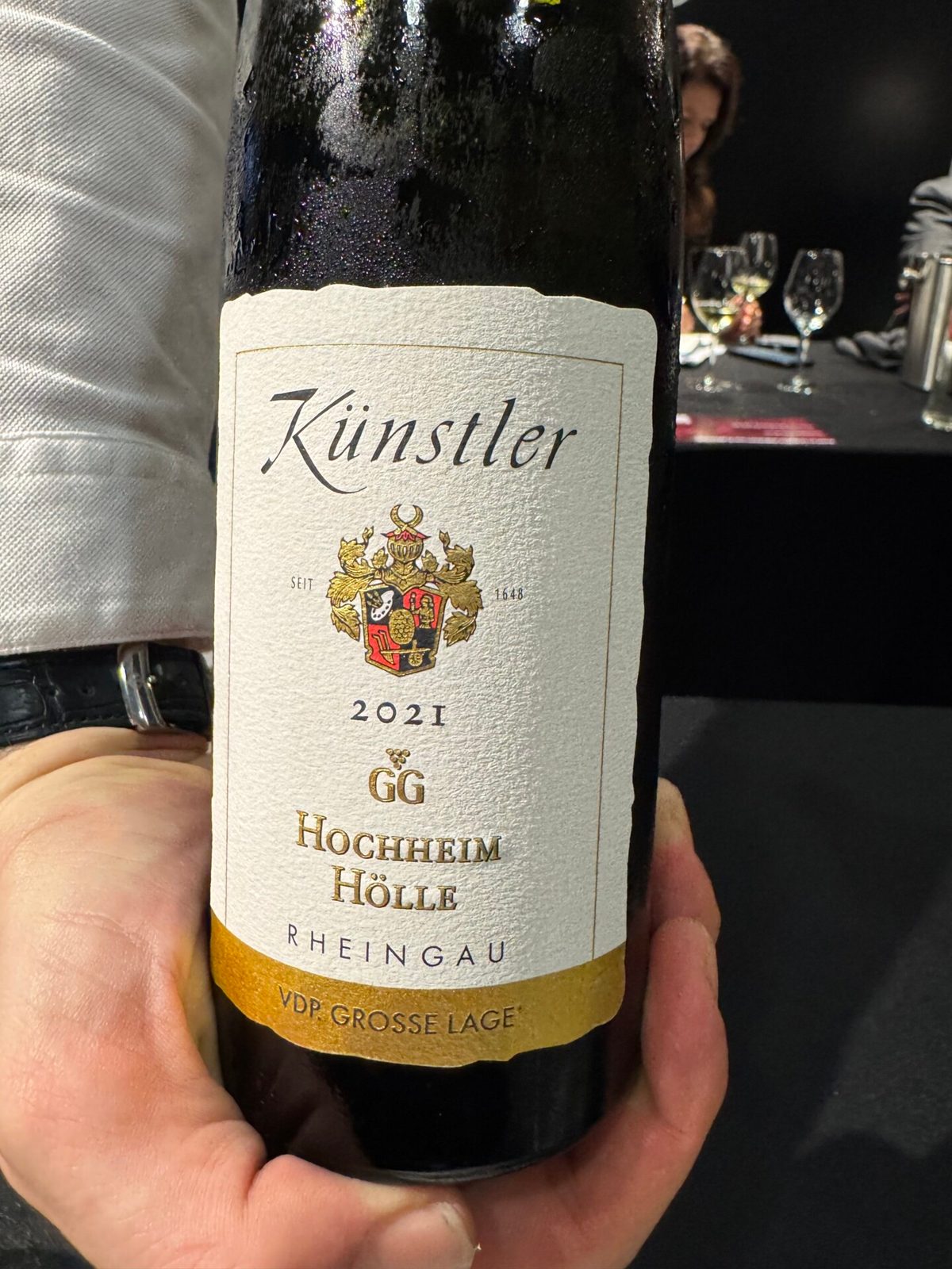 Hand houdt een fles Künstler 2022 GG Hochheim Hölle Riesling uit de Rheingau vast