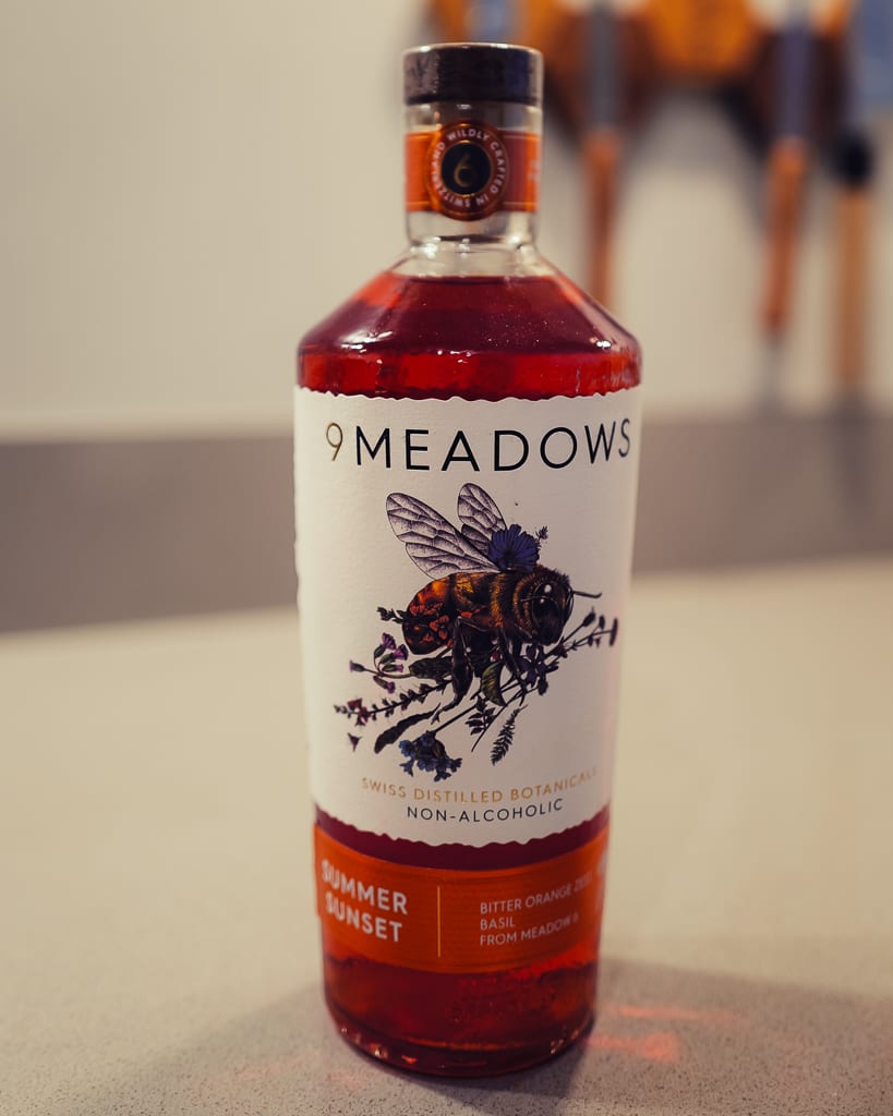 Fles 9 Meadows Summer Sunset met rode alcoholvrije spirit en bij op het etiket