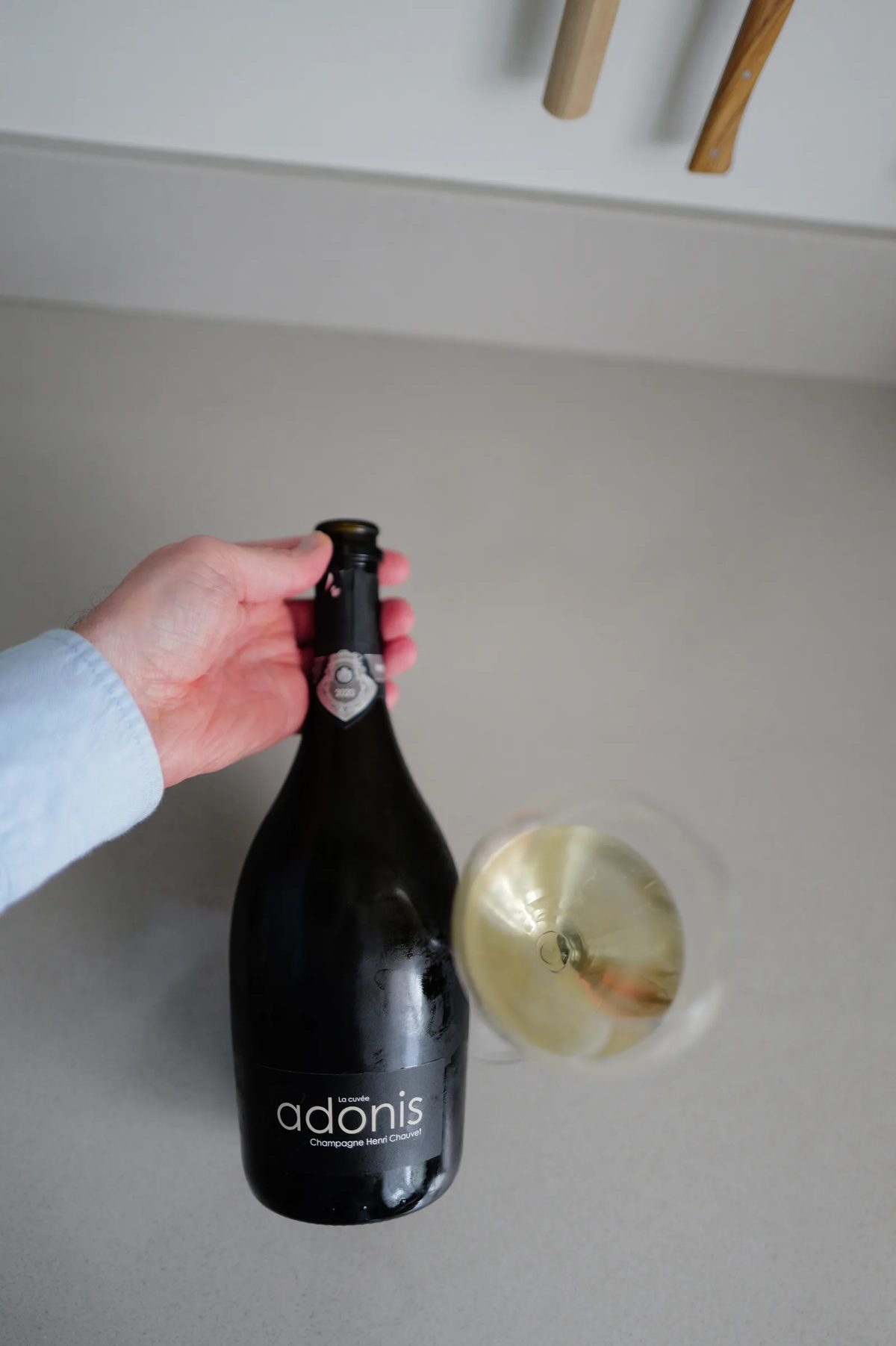 Bottle of Henri Chauvet Adonis 2020 showing the front label, next to a glass of champagne