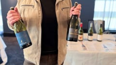 Vincent Gourbon van Famille Gourbon met twee Château Font Barrièle-flessen voor de Costières de Nîmes-tafel