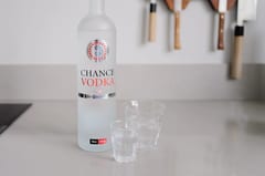 Fles Chance Vodka met roulettelogo naast twee glazen op het aanrecht