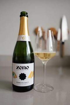 Fles Zeno Sparkling White alcoholvrije mousserende wijn naast een glas