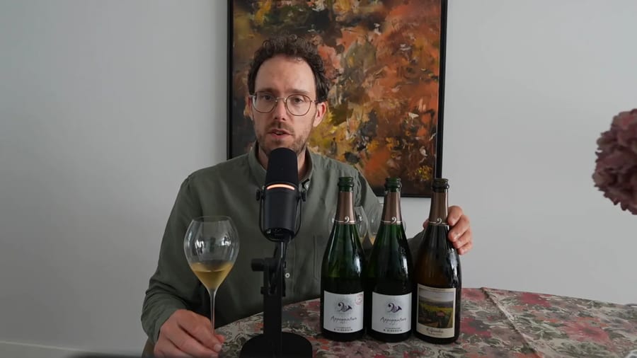 Jeroen Vonk aan tafel met een glas champagne in de hand en drie flessen B. Girardin naast elkaar, tijdens de blindproef over gistrijping