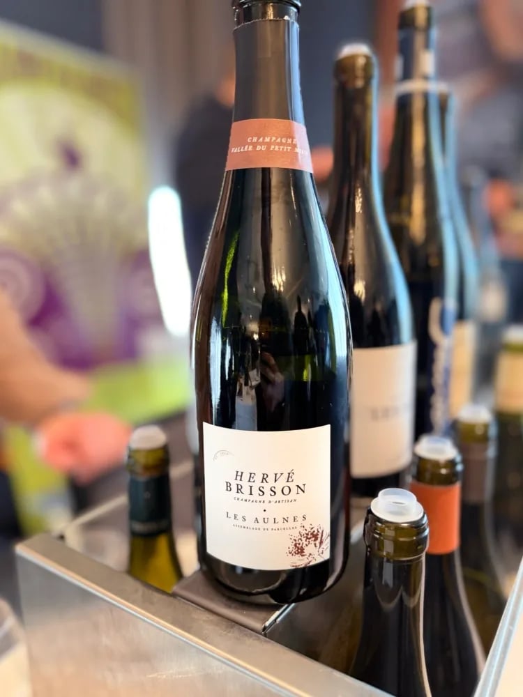 Champagne Hervé Brisson 'Les Aulnes' on the Champagnist table with the purple Champagnist poster behind
