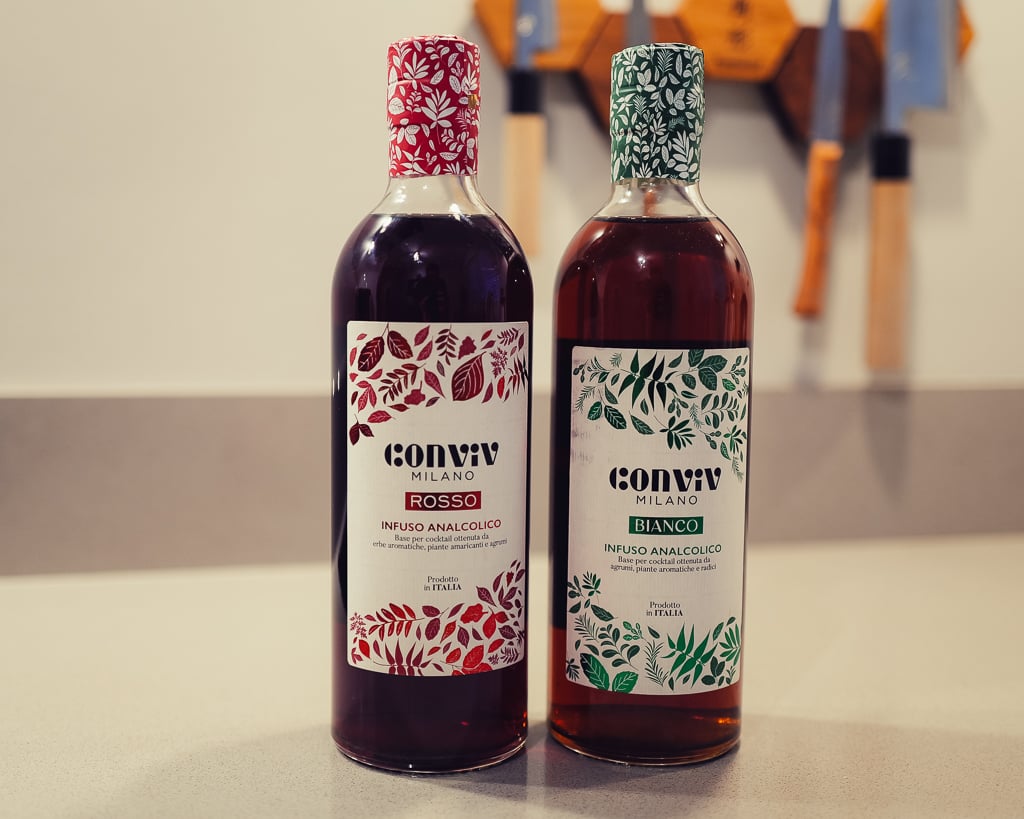 Twee flessen Conviv Milano alcoholvrij, Rosso en Bianco, met bloemmotief-etiketten naast elkaar op een aanrecht