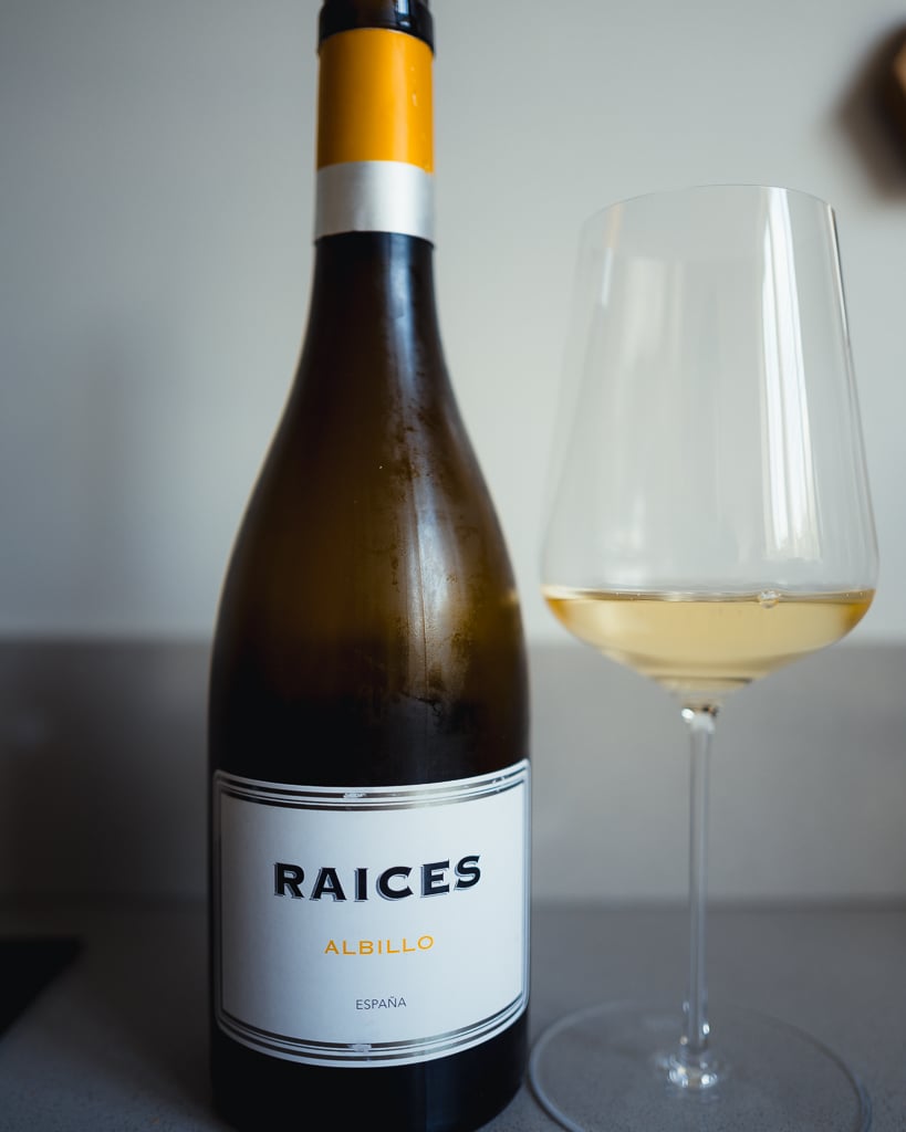 Fles Raíces Albillo witte wijn uit Spanje naast een glas goudgele wijn