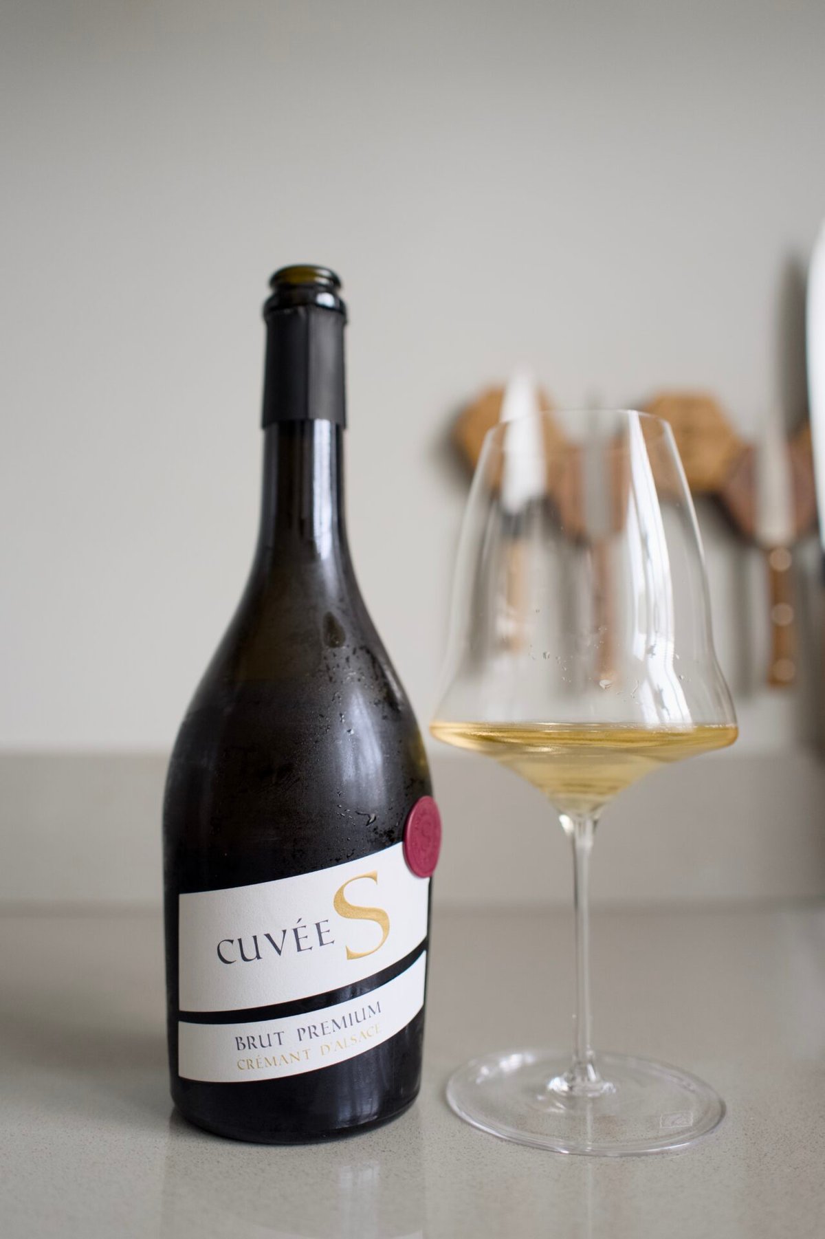Fles Cuvée S Brut Premium Crémant d'Alsace naast een glas mousserende wijn