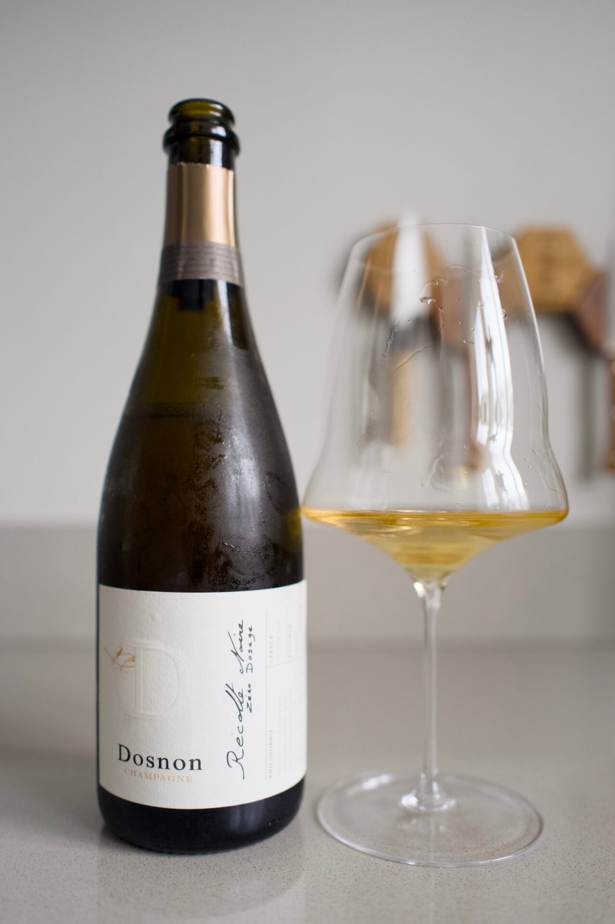 Fles Dosnon Champagne naast een glas goudgele champagne