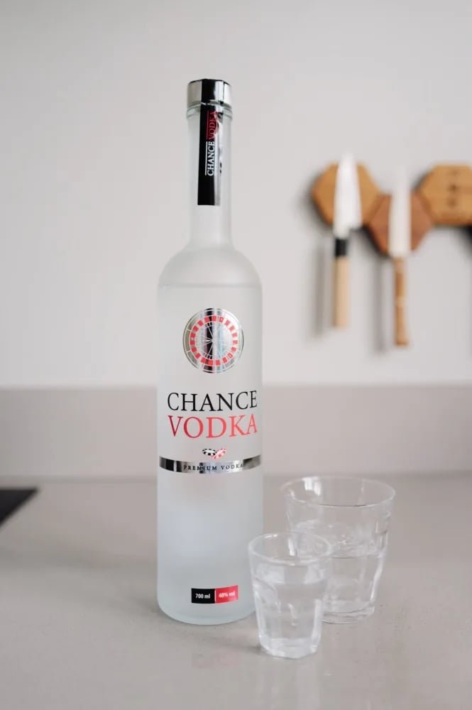 Fles Chance Vodka met roulettelogo naast twee glazen op het aanrecht