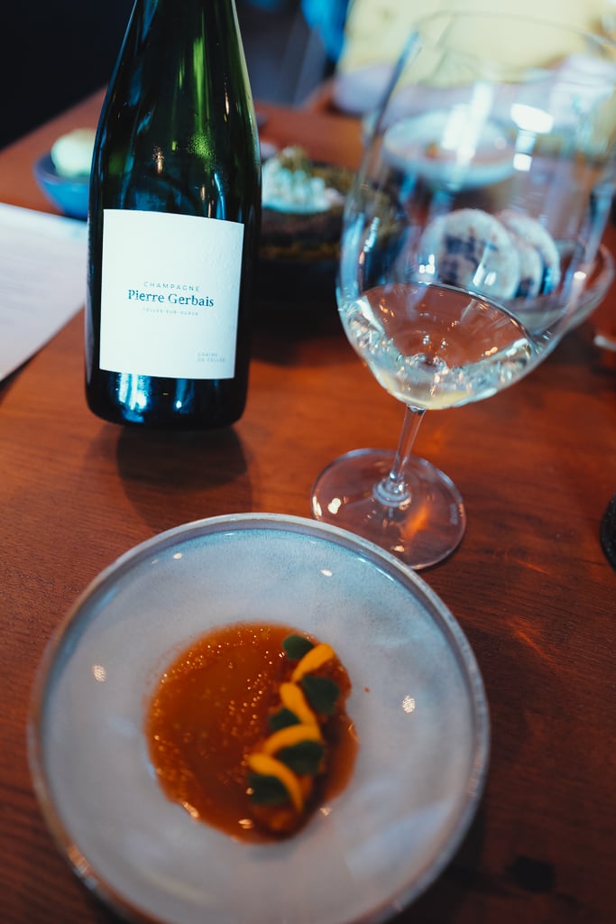 Fles Champagne Pierre Gerbais bij een glas en een voorgerecht op een houten tafel