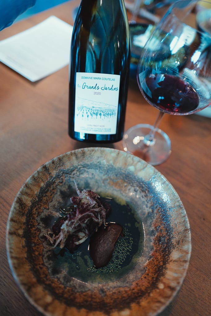 Fles Domaine Marx Coutelas Les Grands Jardins Pinot Noir naast een glas rode champagne en een gerecht