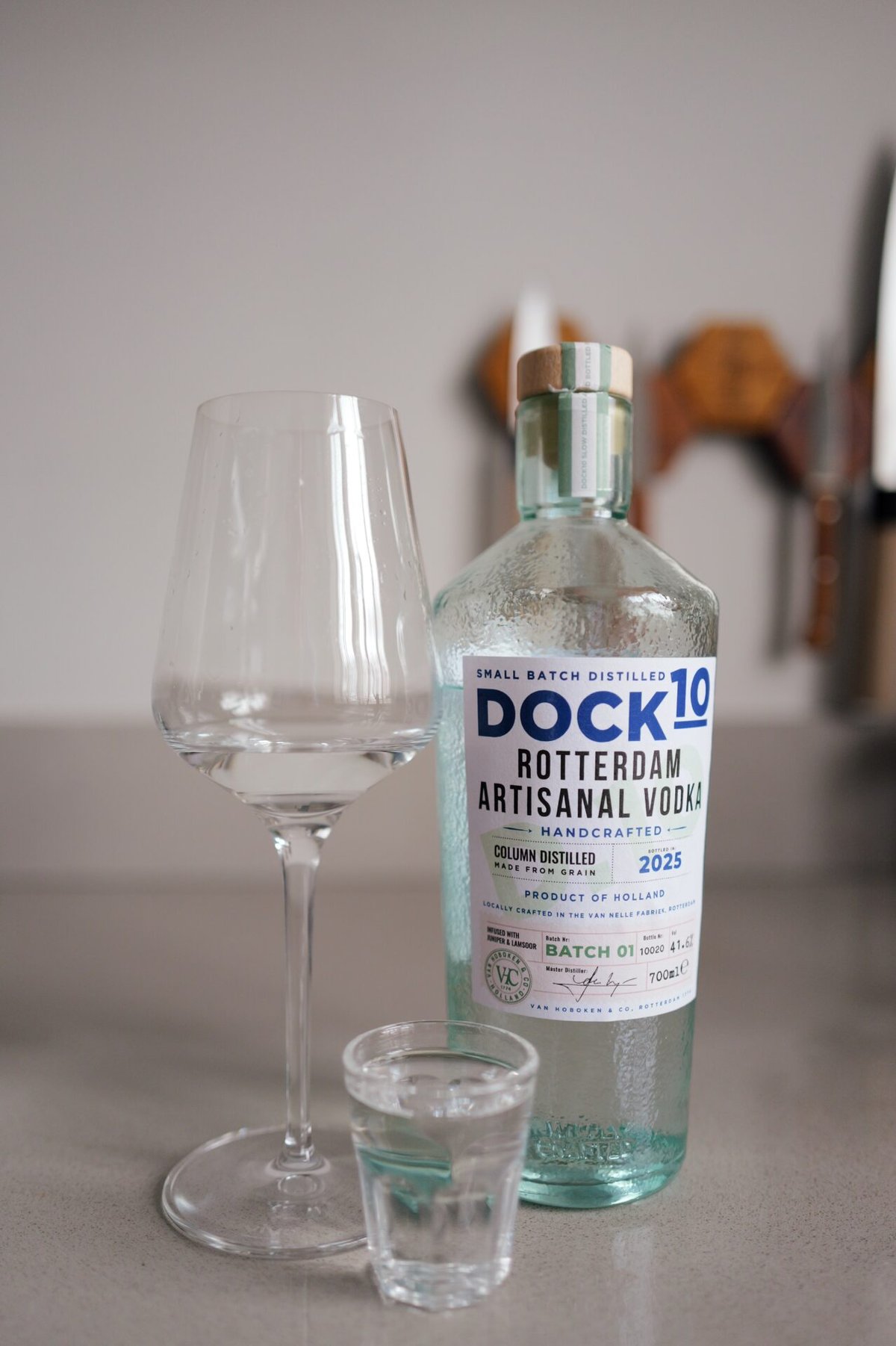 Fles DOCK10 vodka met leeg wijnglas en gevuld borrelglaasje op een aanrecht