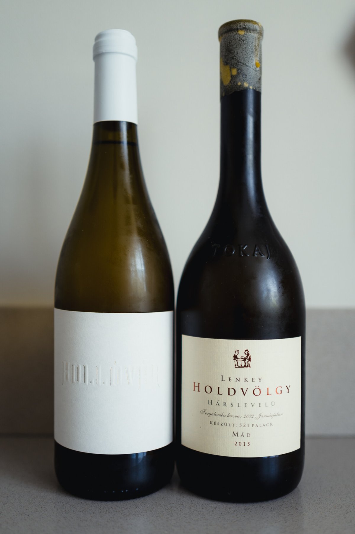 Twee Tokaji-flessen naast elkaar: blanco Hollóvár links en Lenkey Holdvölgy Hárslevelű 2015 rechts