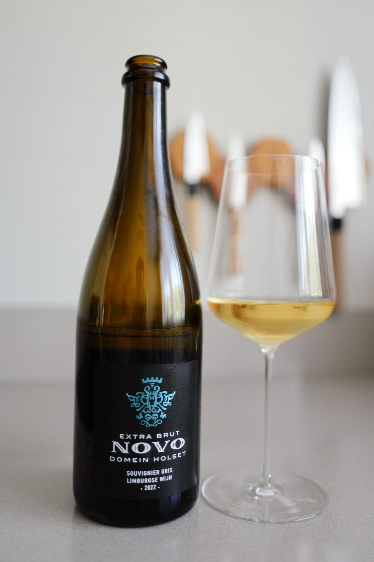 Fles Domein Holset Novo Extra Brut Souvignier Gris 2022 met glas goudgele mousserende wijn