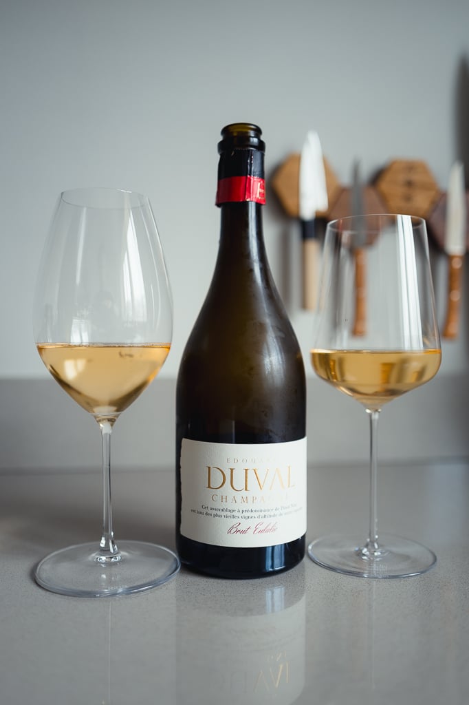 Fles Edouard Duval Brut Eulalie met rood kapsel tussen twee glazen goudgele champagne