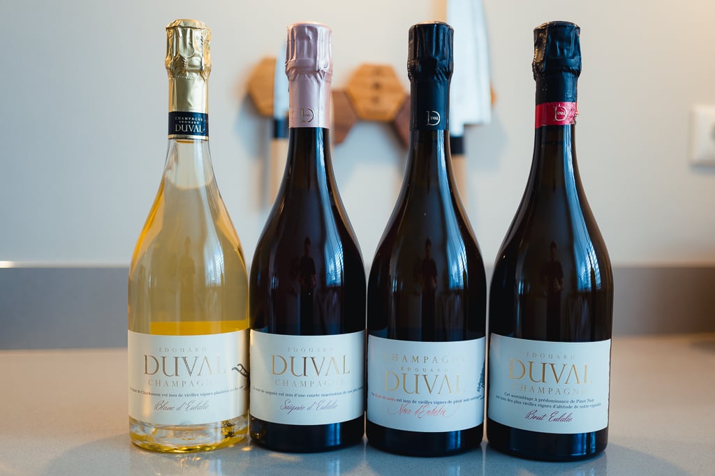 Vier flessen Edouard Duval champagne op een rij met goud, roze, zwart en rood foliekapsel