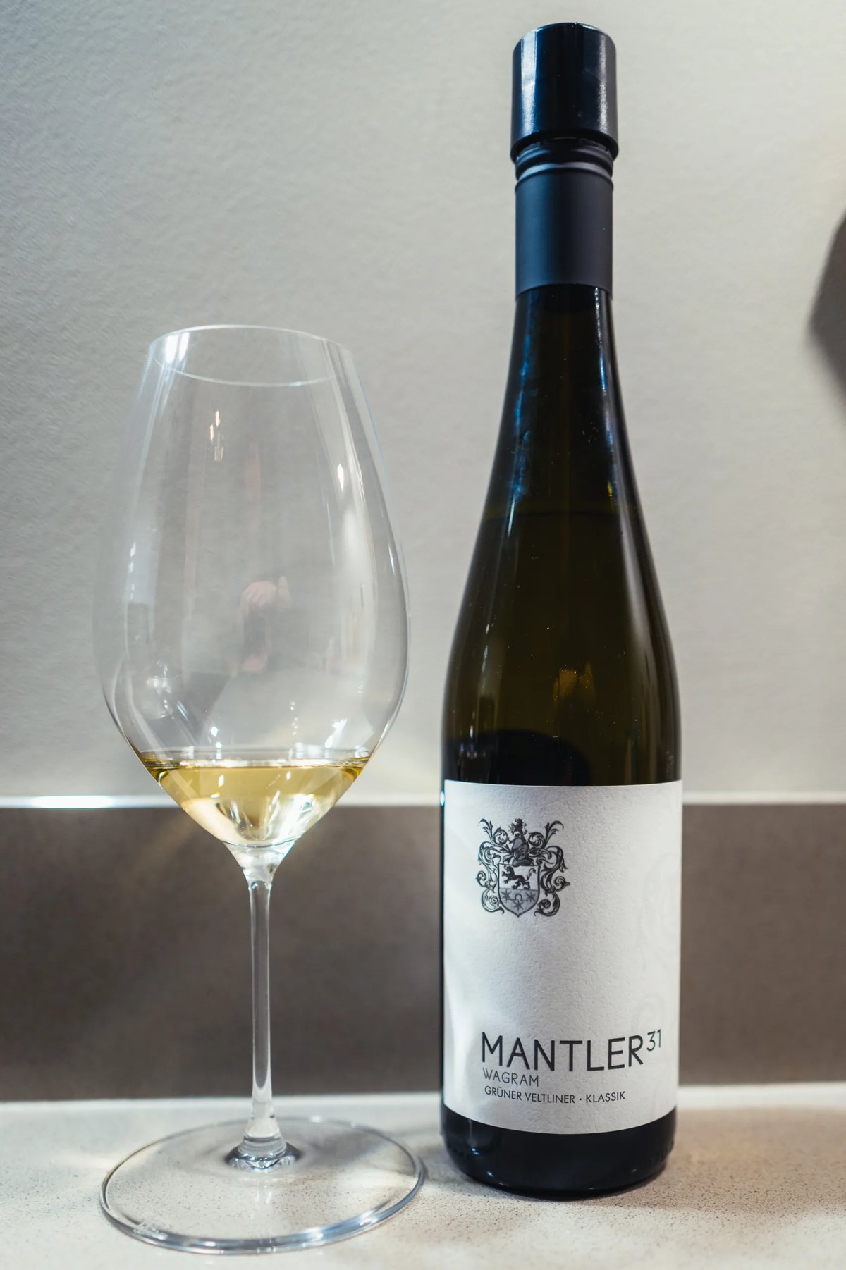 Fles Mantler 31 Grüner Veltliner uit Wagram met glas lichtgele wijn