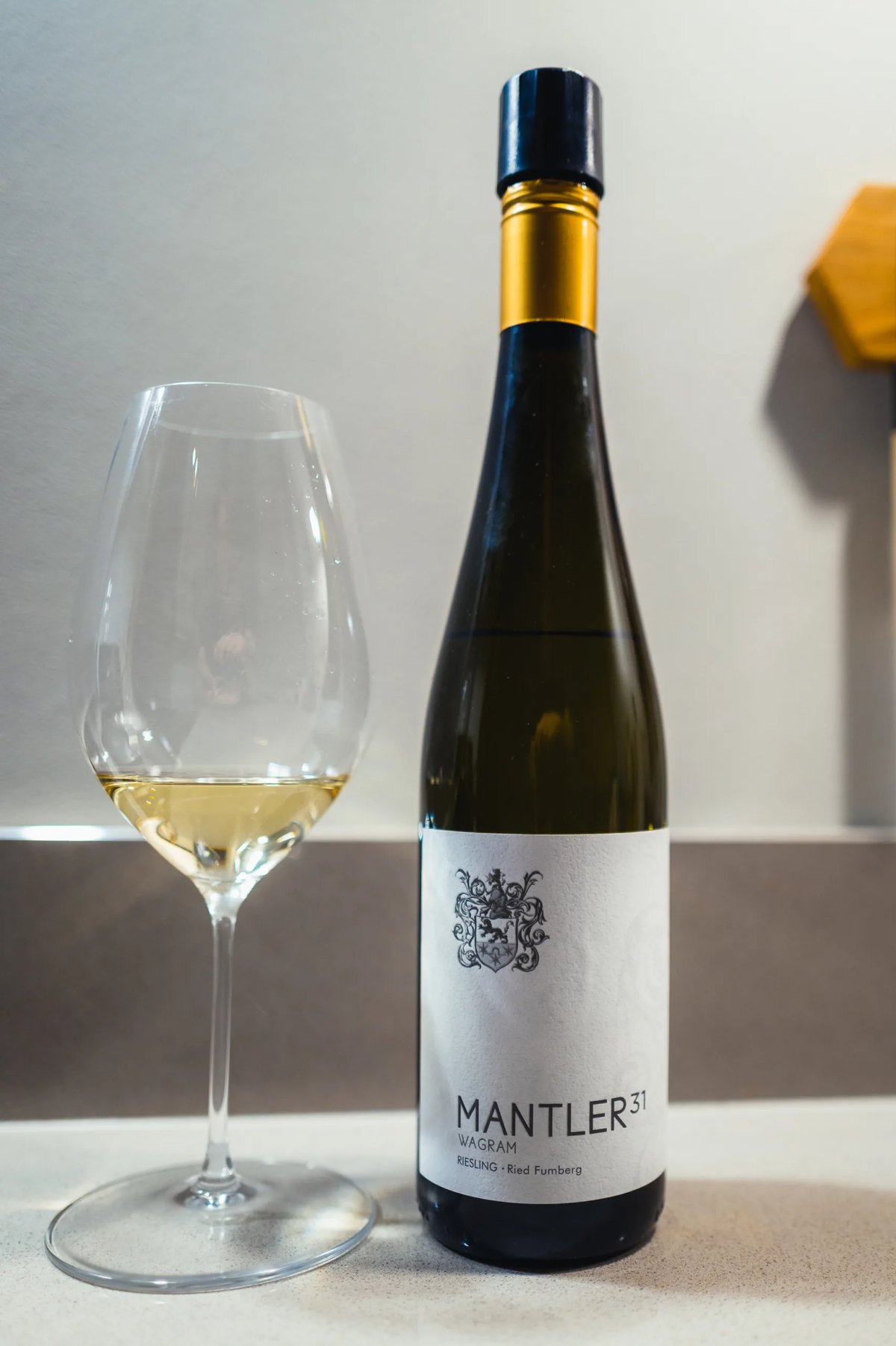 Fles Mantler 31 Riesling Ried Fumberg uit Wagram met goudkapsel en glas lichtgele wijn