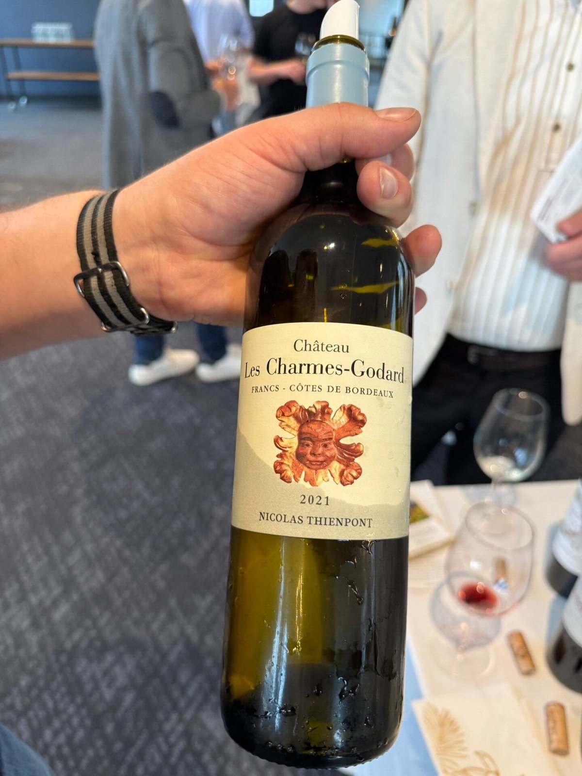 Hand houdt fles Château Les Charmes-Godard Francs Côtes de Bordeaux 2021 van Nicolas Thienpont