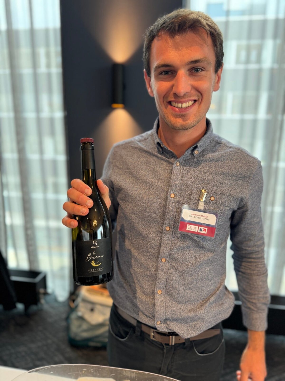 Lachende man in blauw overhemd houdt fles Domaine des Brissettes Le Berceau Cheverny vast