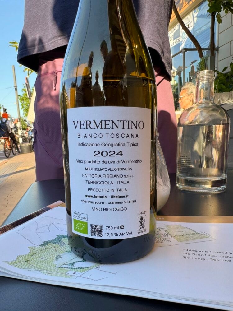 Achterkant fles Fibbiano Vermentino Bianco Toscana 2024 op een tafel buiten op een terras