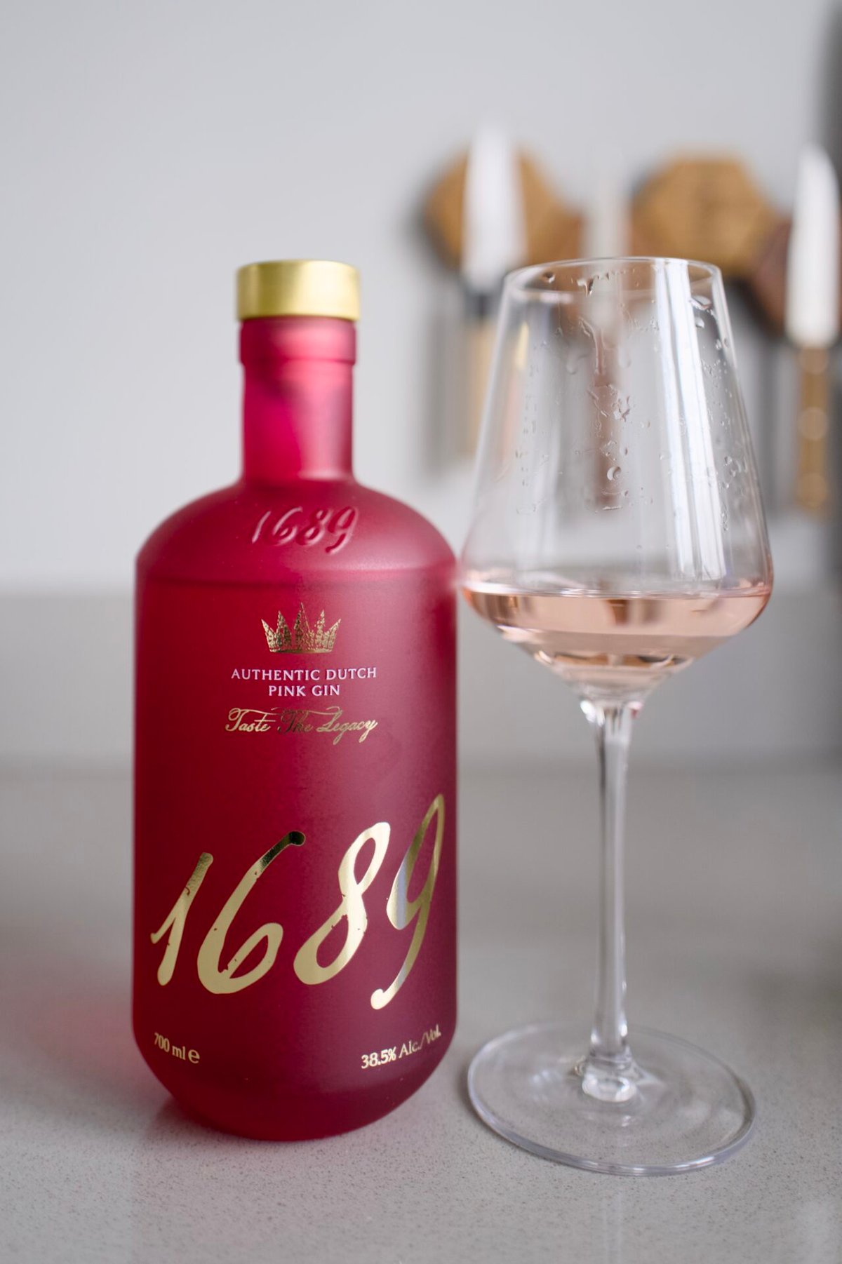 Roze fles 1689 Authentic Dutch Pink Gin naast een glas met lichtroze drank
