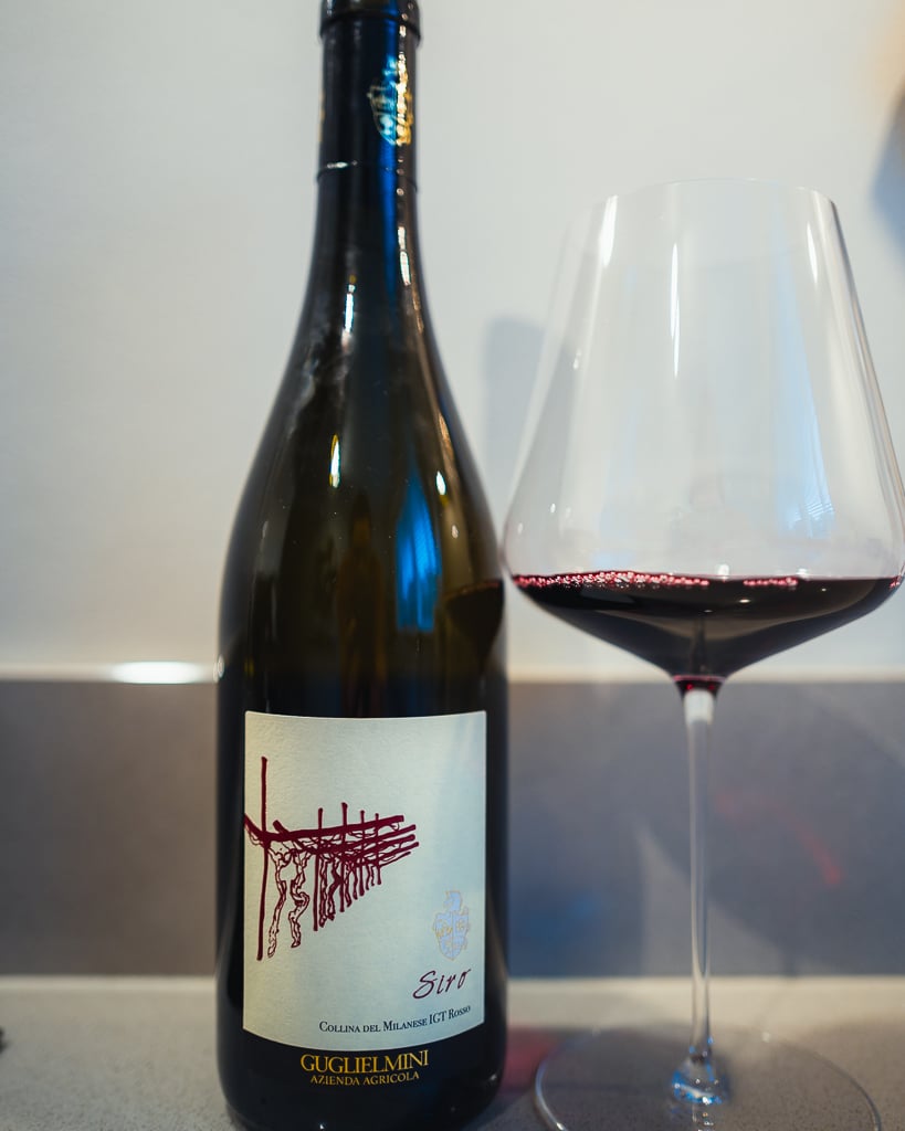 Fles Siro Collina del Milanese van Guglielmini met wijnstok-etiket naast een glas rode wijn