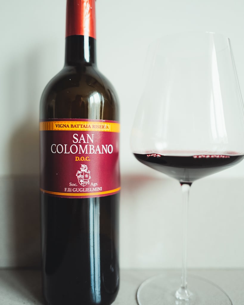 Fles San Colombano Vigna Battaia Riserva van Guglielmini naast een glas rode wijn