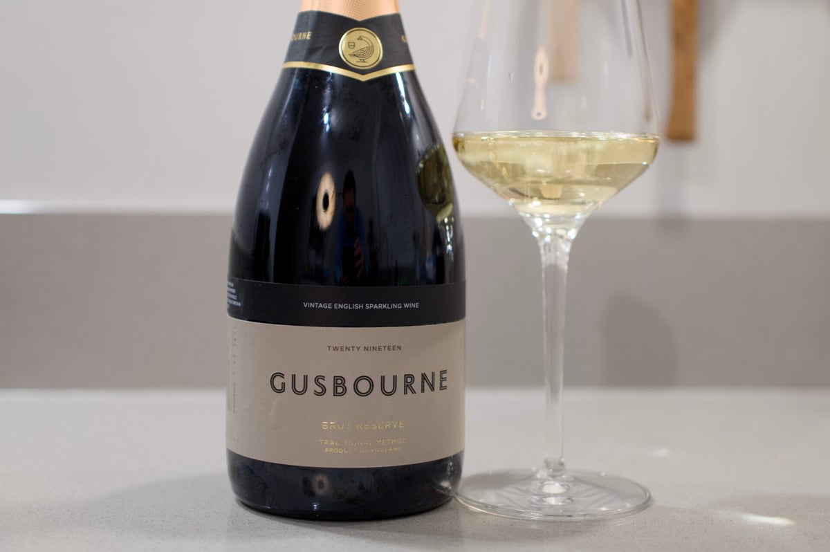 Fles Gusbourne Brut Reserve 2019 naast een glas mousserende witte wijn