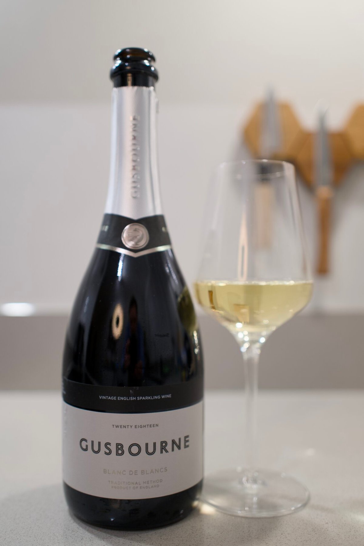 Fles Gusbourne Blanc de Blancs 2018 naast een glas witte wijn