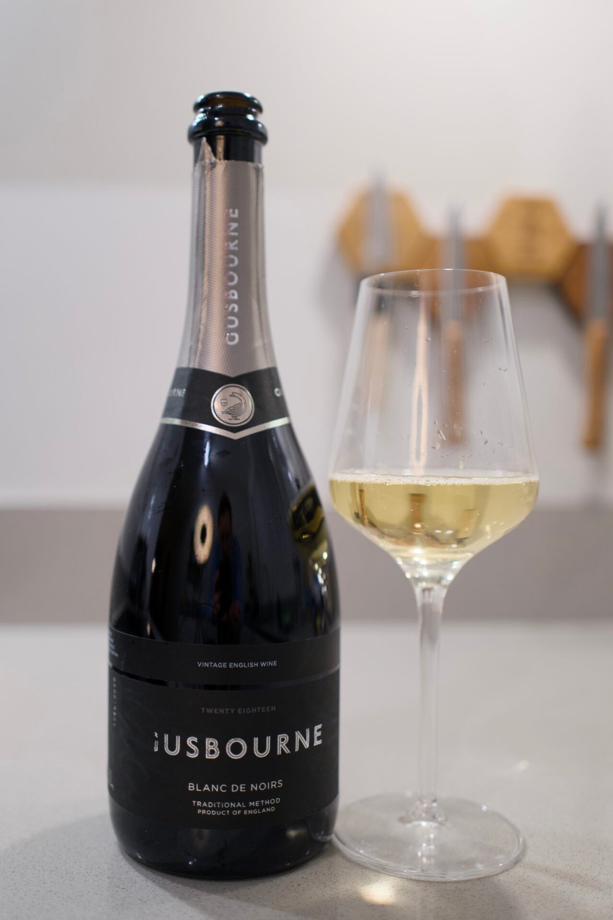 Fles Gusbourne Blanc de Noirs 2018 naast een glas witte wijn