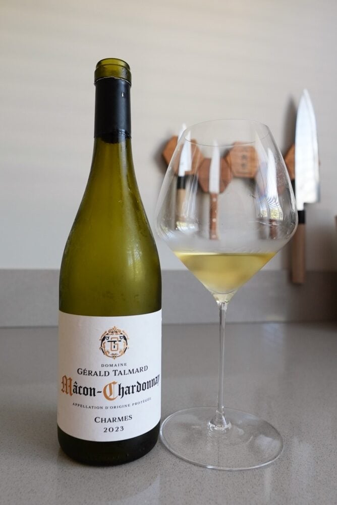 Fles Domaine Gérald Talmard Mâcon-Chardonnay Charmes 2023 naast een glas witte wijn