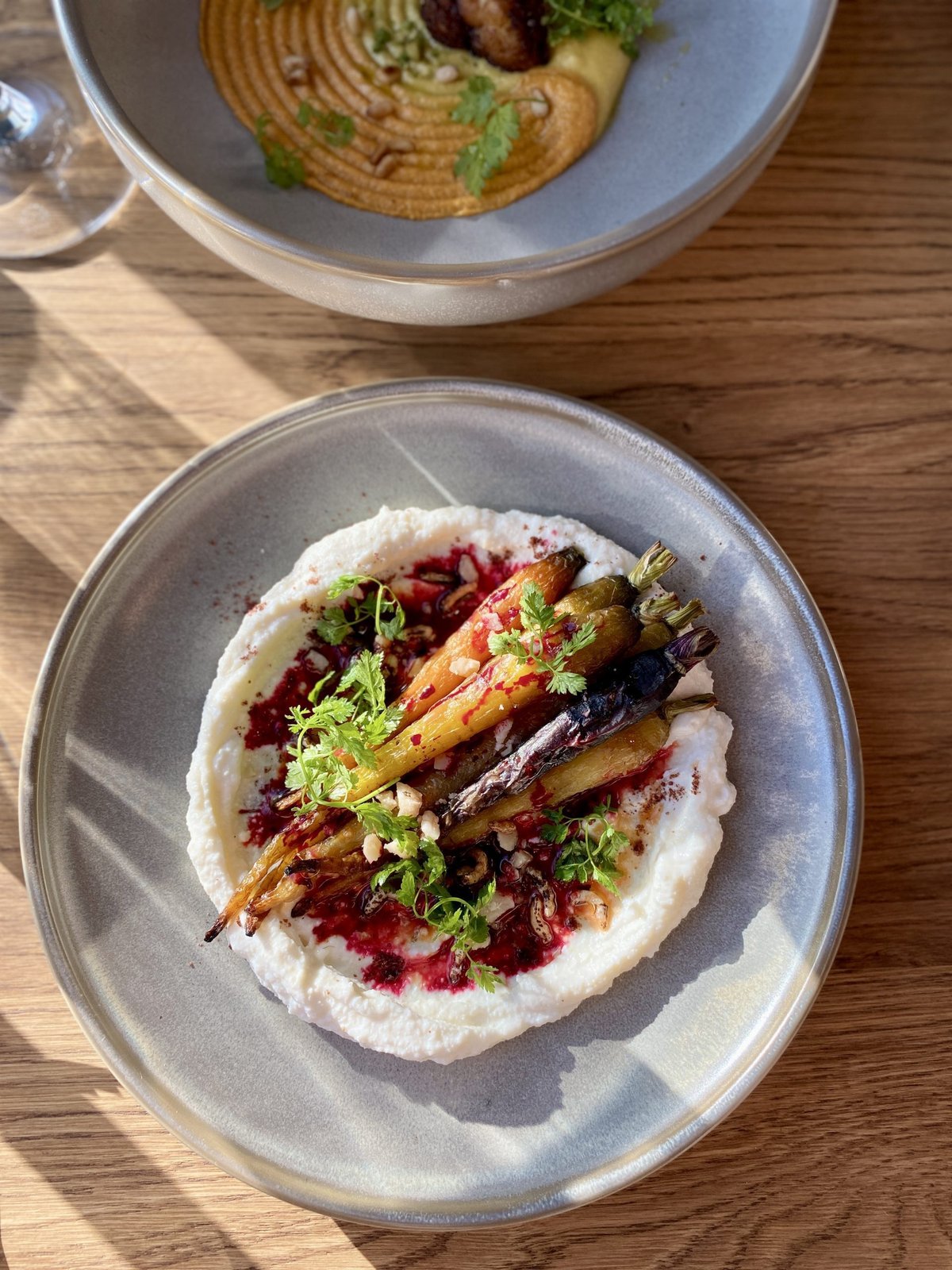 Bord met geroosterde worteltjes op ricotta met granaatappel en kruiden