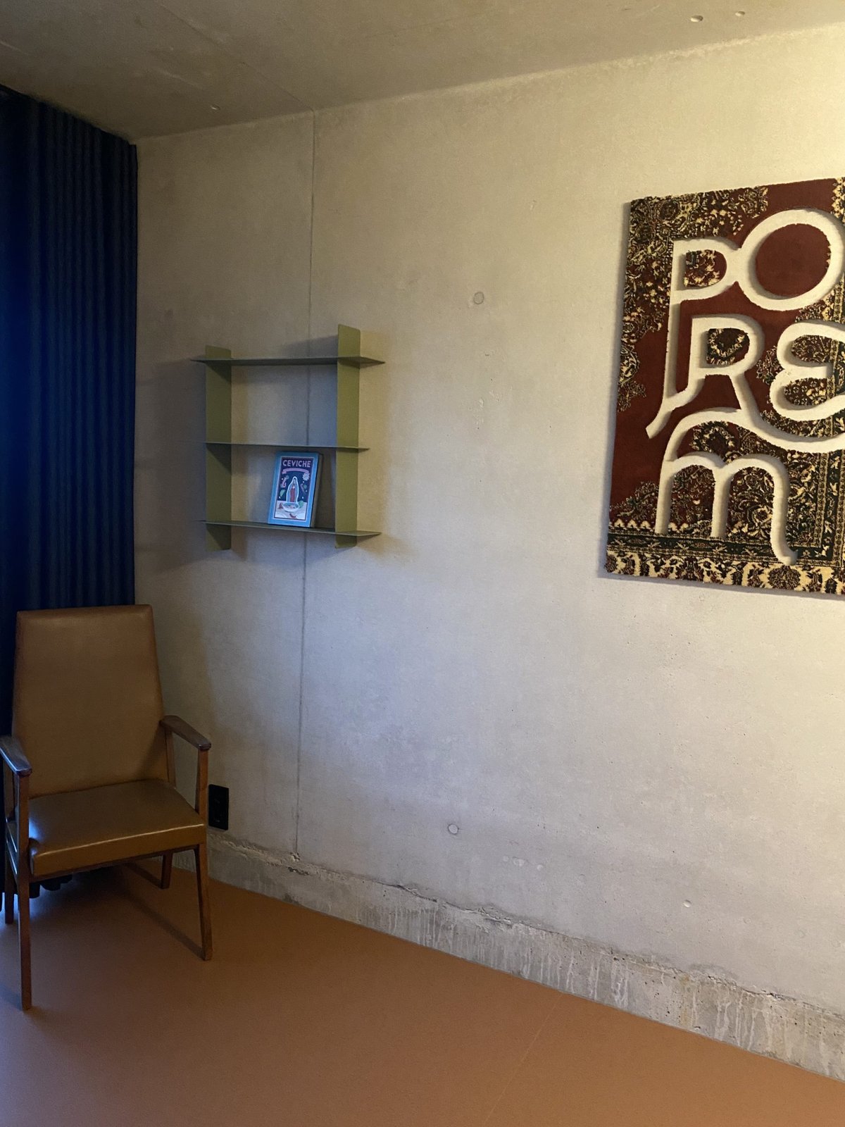 Betonnen muur met kunstwerk met de letters POREM, een leesplank en een houten stoel