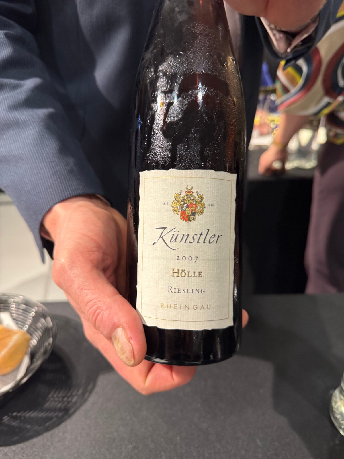 Hand holding a Kunstler 2007 Holle Riesling Rheingau bottle at the tasting