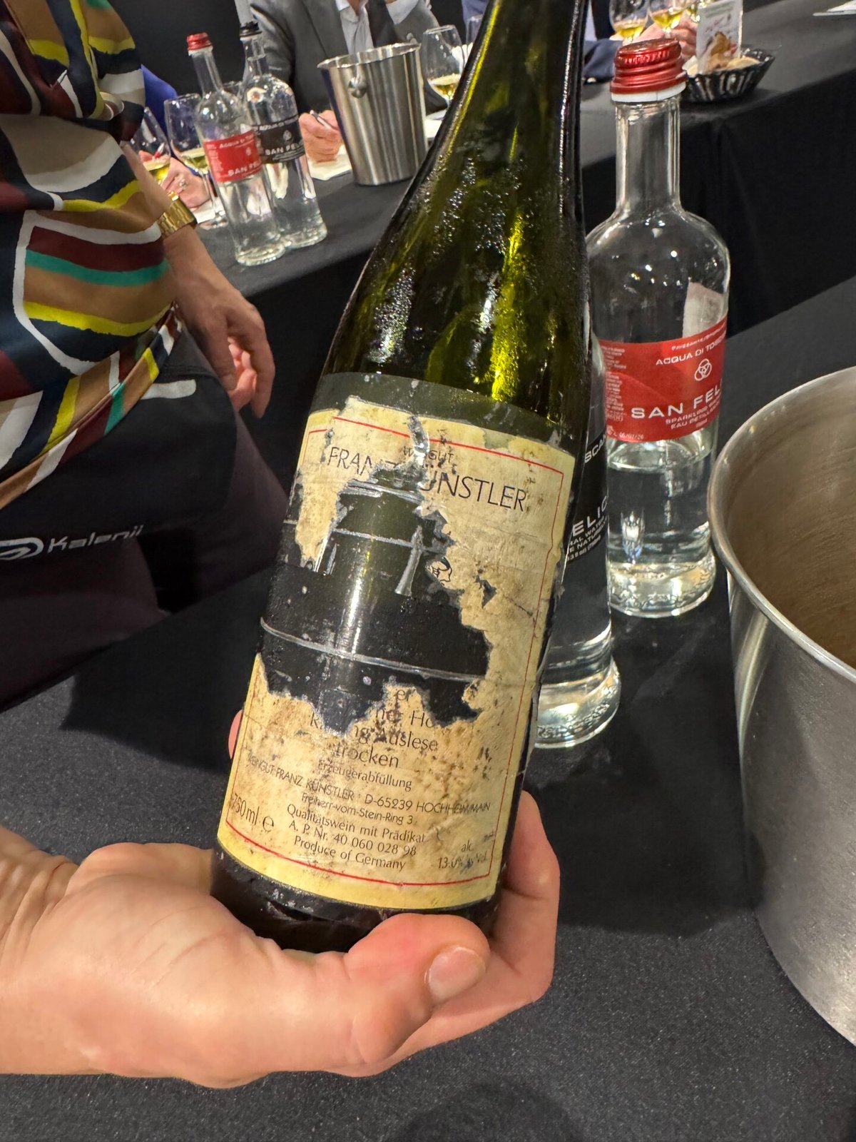 Hand holding an aged Franz Kunstler 1997 Auslese bottle with a faded, weathered label