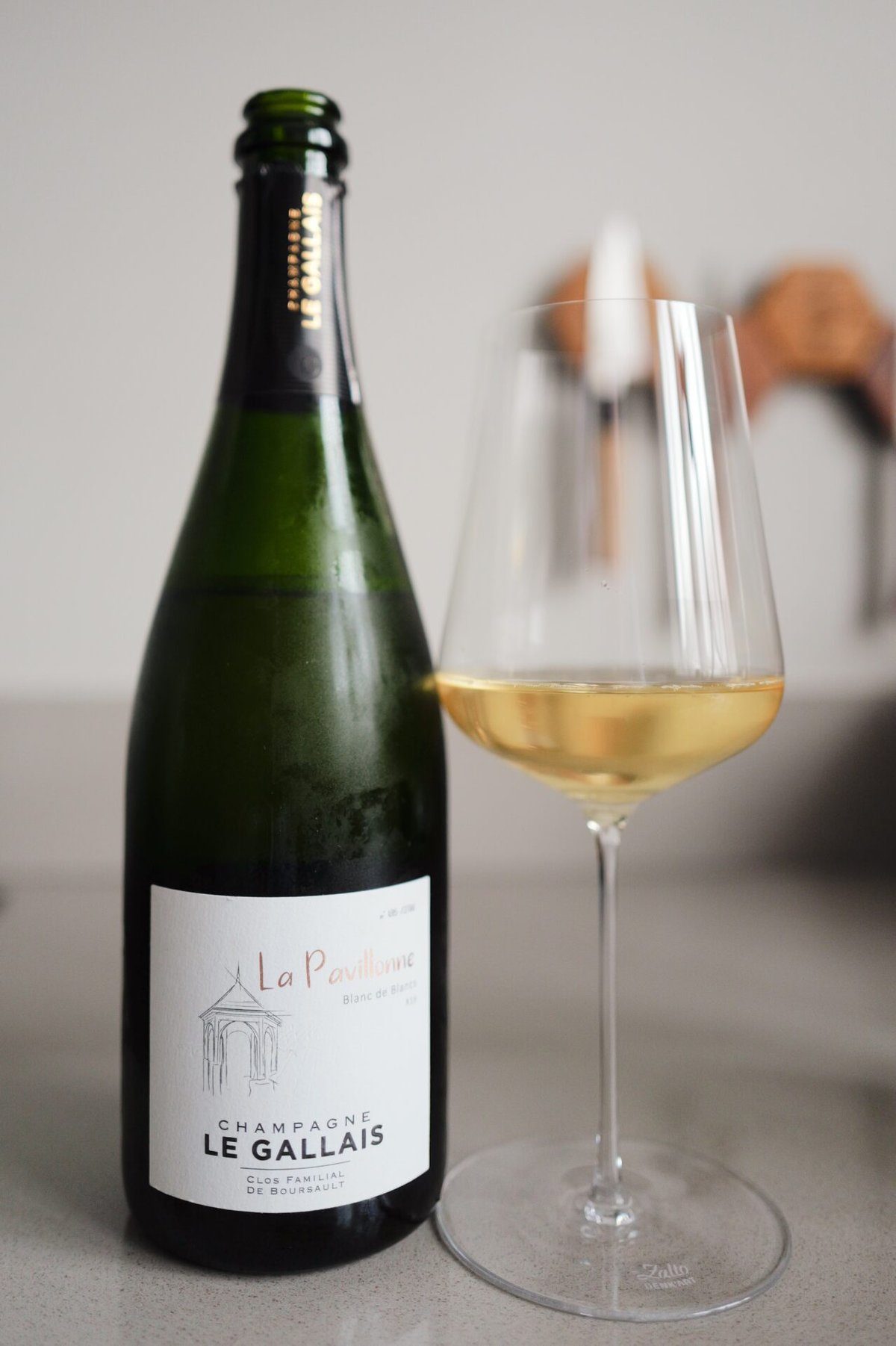Groene fles La Pavillonne van Champagne Le Gallais naast een glas lichtgouden champagne op een aanrecht