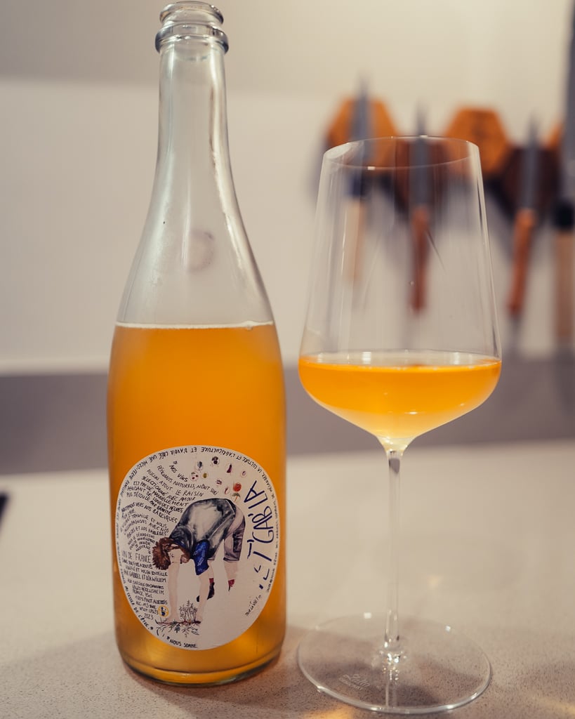 Fles Pet'Gab'La pétillant naturel met troebele oranje wijn en geïllustreerd etiket naast een gevuld glas