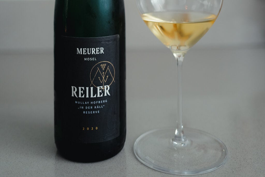 Donkere fles Meurer Reiler Mullay-Hofberg In der Käll Reserve 2020 naast een glas goudkleurige riesling