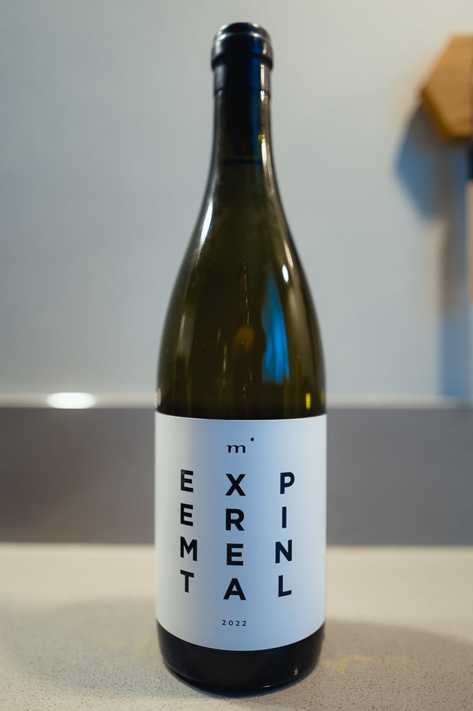 Fles Minimalist EXPERIMENTAL met wit etiket alleen op een aanrecht voor een grijze muur