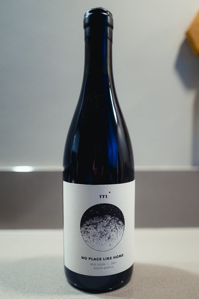 Fles Minimalist No Place Like Home Syrah alleen op een aanrecht voor een grijze muur