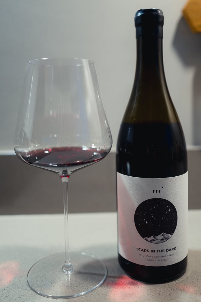 Fles Minimalist Stars in the Dark uit Cape Agulhas naast een glas rode wijn op een aanrecht