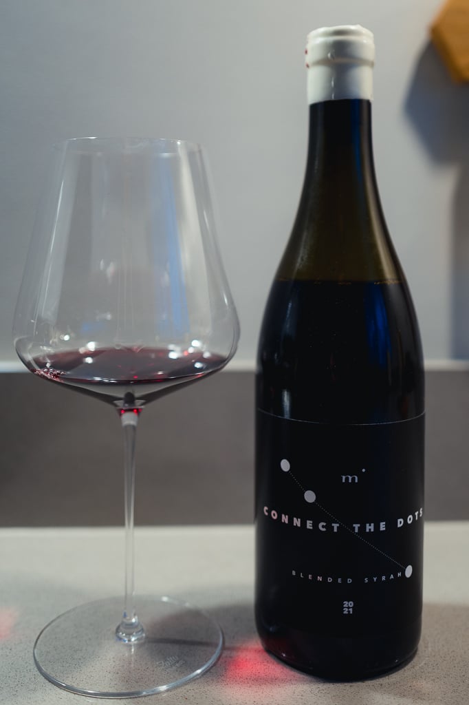 Fles Minimalist Connect the Dots Blended Syrah met witte capsule naast een glas rode wijn