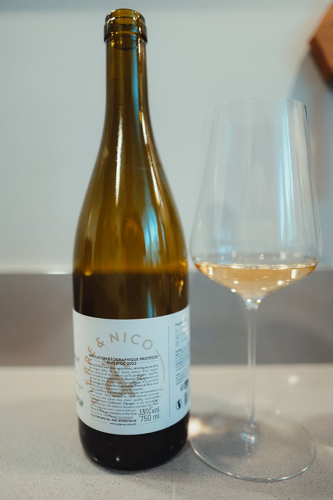 Fles Pierre & Nico Pays d'Oc met rugetiket naast glas lichtgele wijn op aanrecht