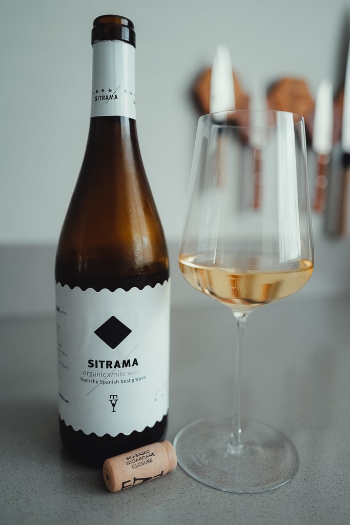 Fles Sitrama organic white wine naast glas goudkleurige wijn met kurk ervoor