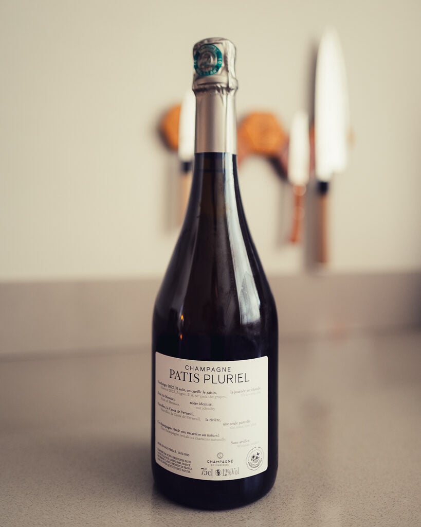 Fles Champagne Patis Pluriel met rugetiket en groene capsule op aanrecht