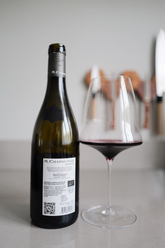 Rugetiket van fles M. Chapoutier Sizeranne Hermitage naast glas rode wijn